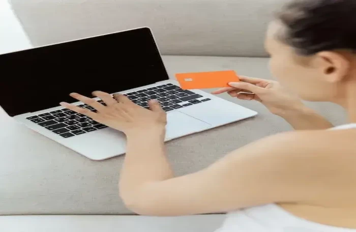  woman holding a bank card and using laptop small