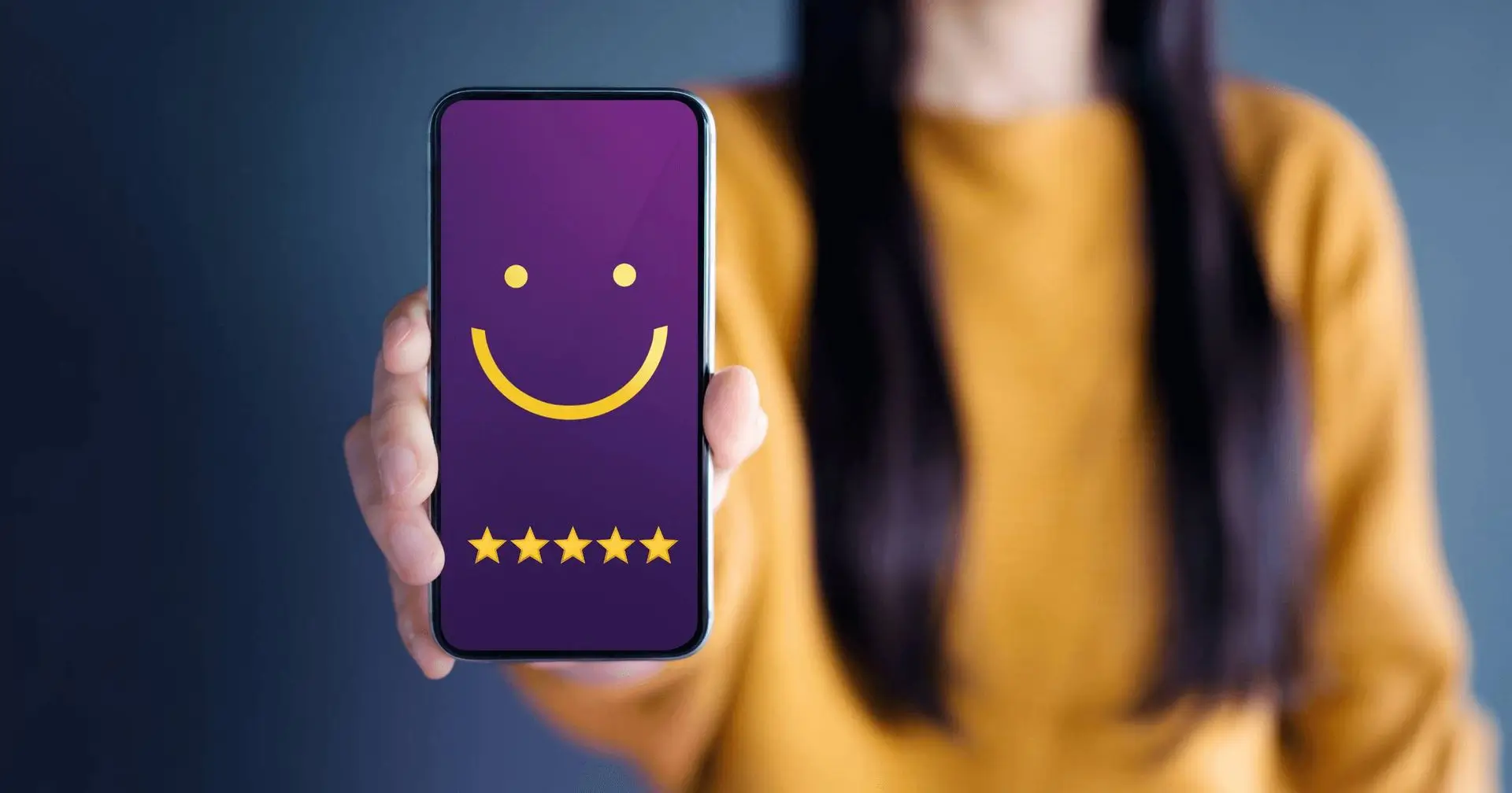 A woman is holding a phone with a smile emoji and 5-star ratings