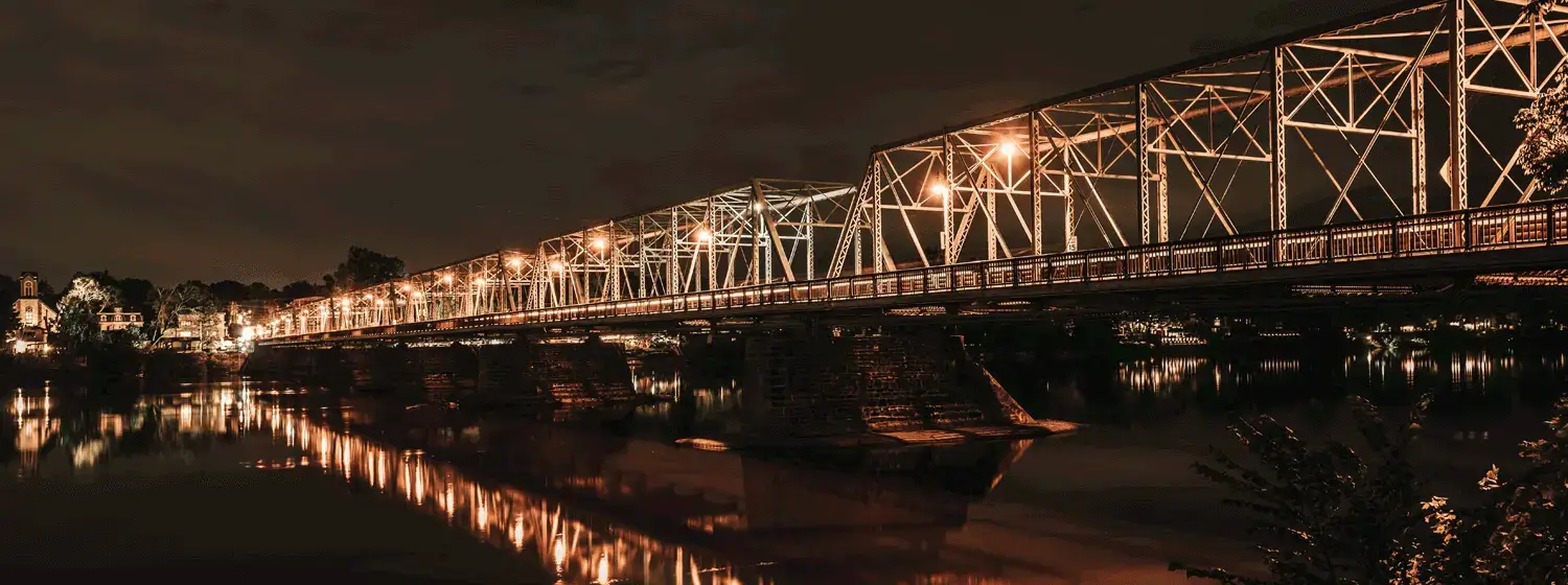 The New Hope-Lambertville Bridge, a six-span steel truss bridge illuminated at night