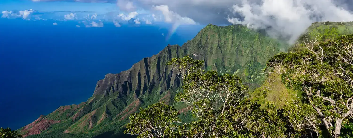 A high-angle view of the dramatic cliffs and lush green valleys of Kalalau Valley, Kauai, Hawaii.